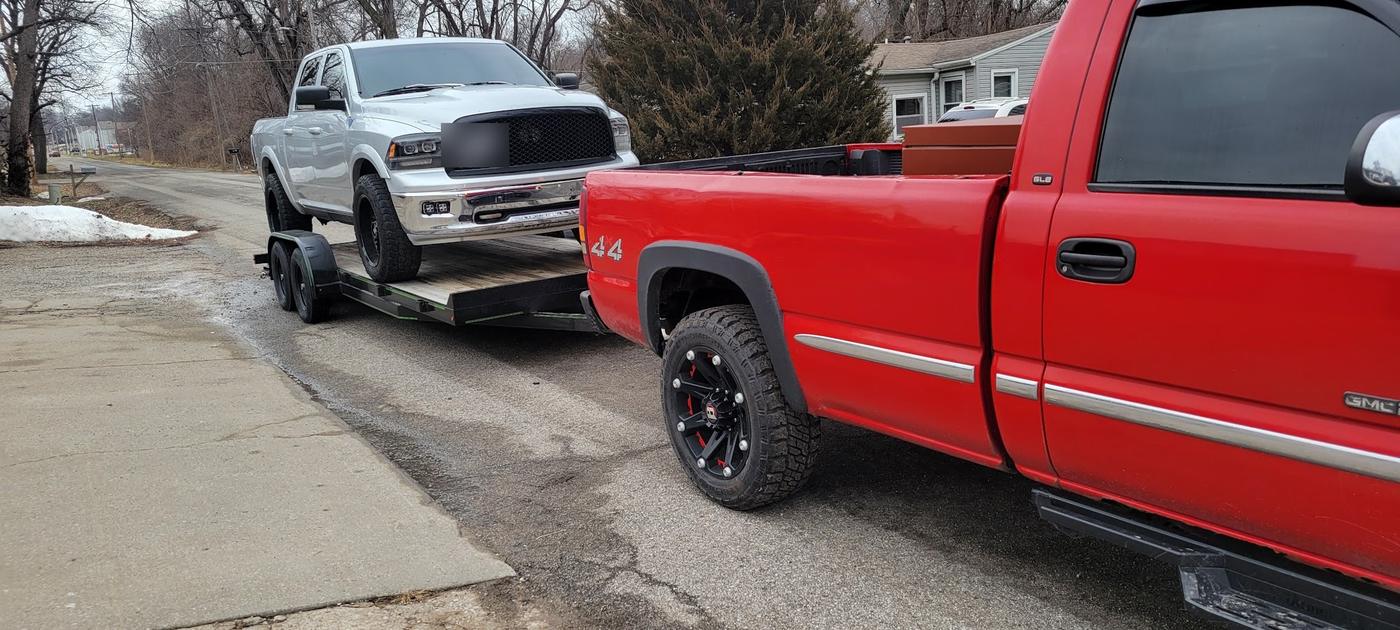 A pickup towing a trailer with another truck loaded on it